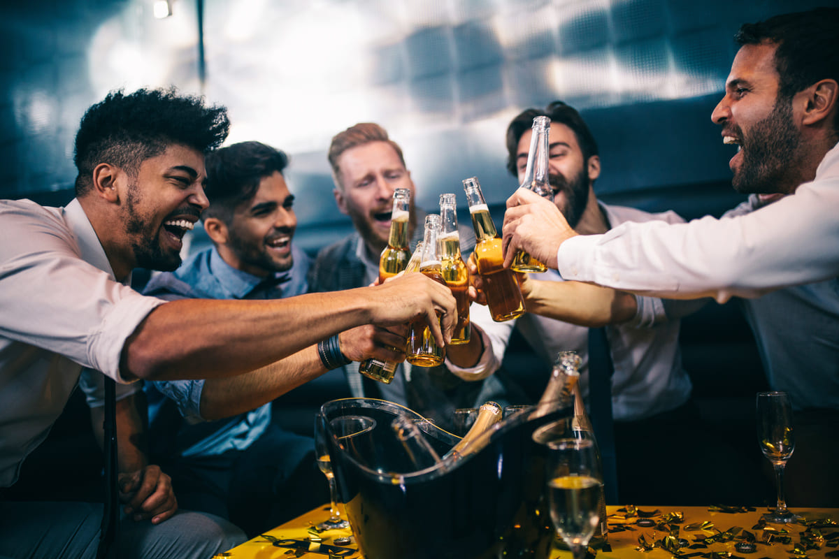 Eine fröhliche Männergruppe stößt mit Bierflaschen und Gläsern an