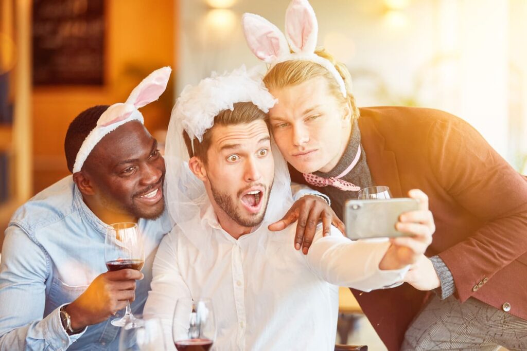 Junggesellenabschied, Männer mit Hochzeitsschleier und Hasenohren feiern gemeinsam