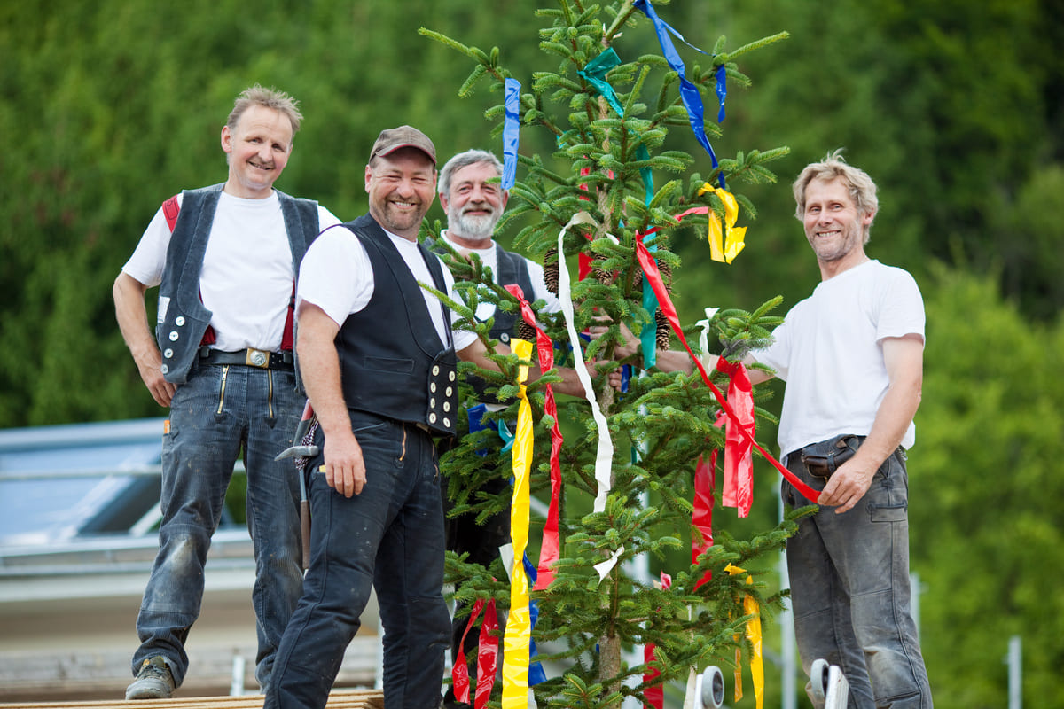 Handwerker stehen vor Richtfestbaum